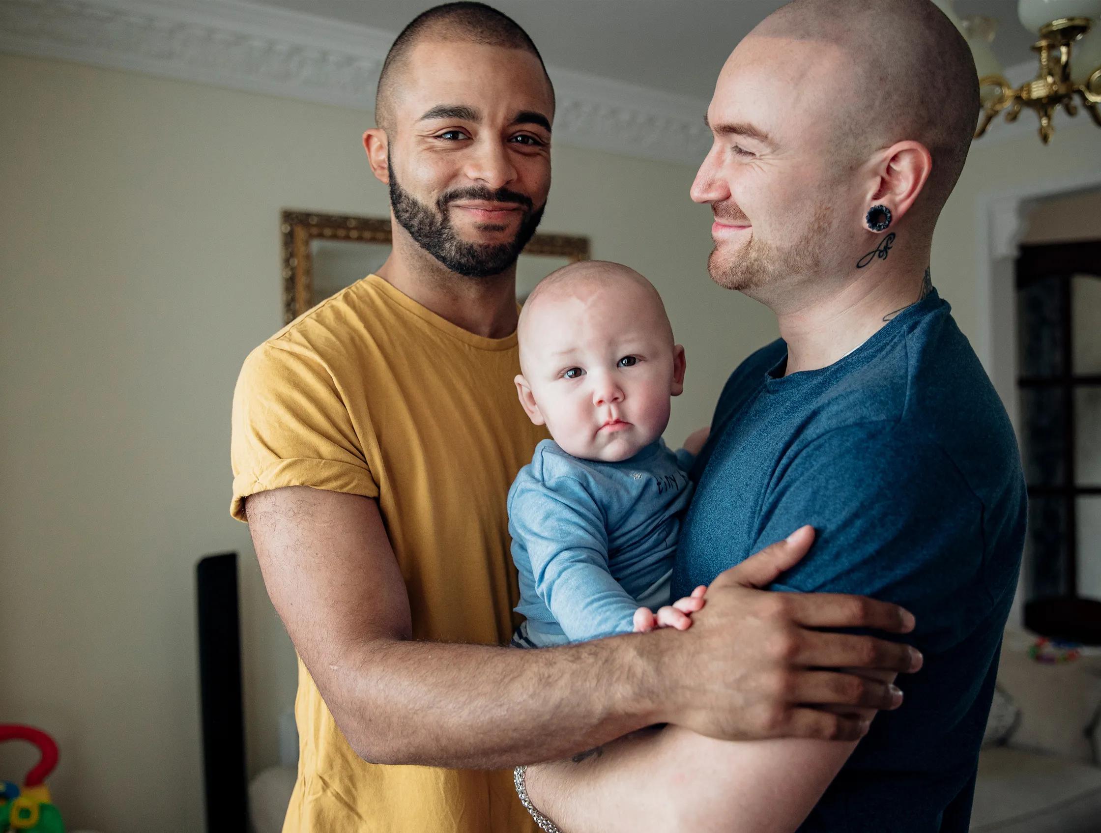 Two men holding their baby child