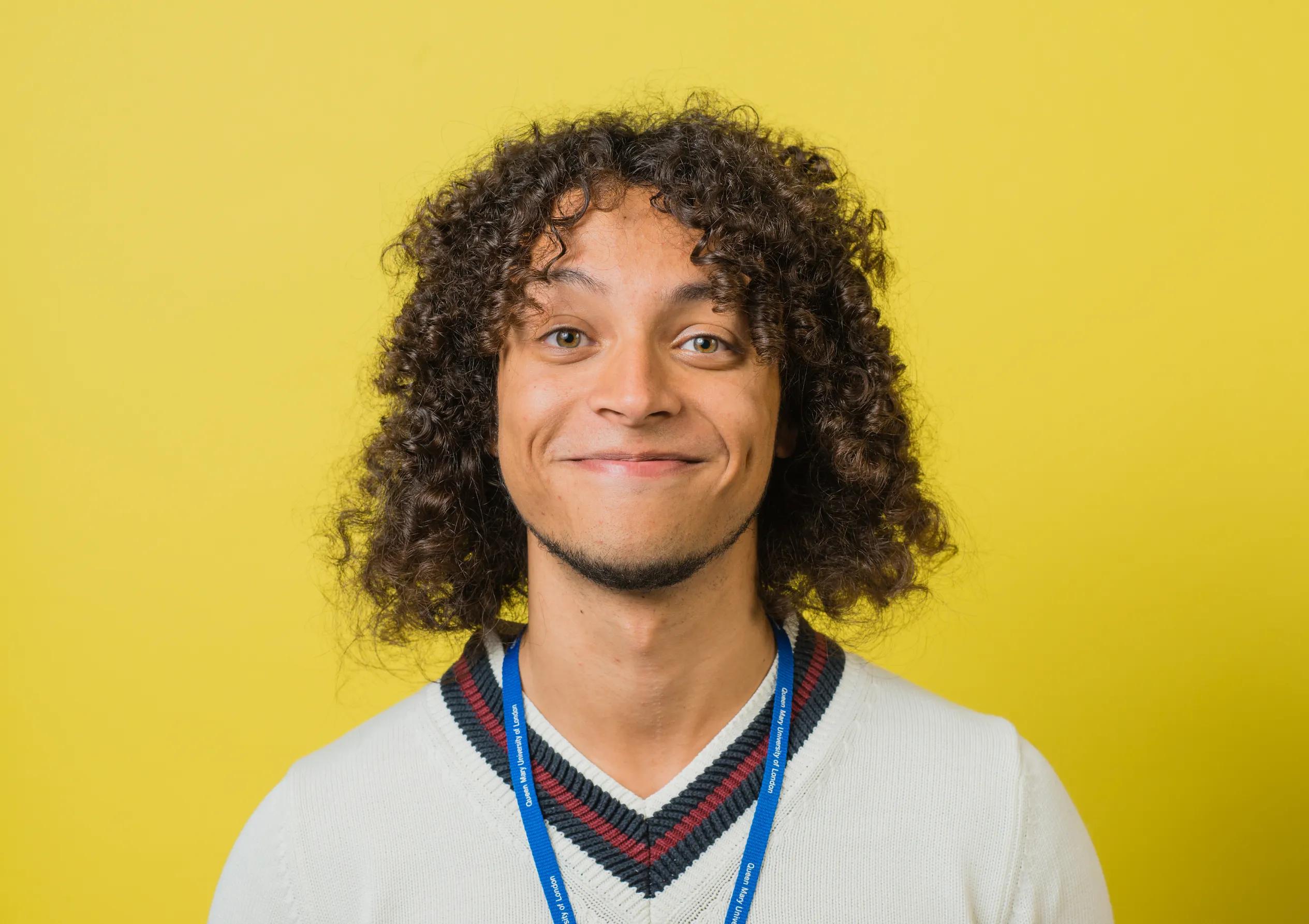 University student smiling with a yellow background