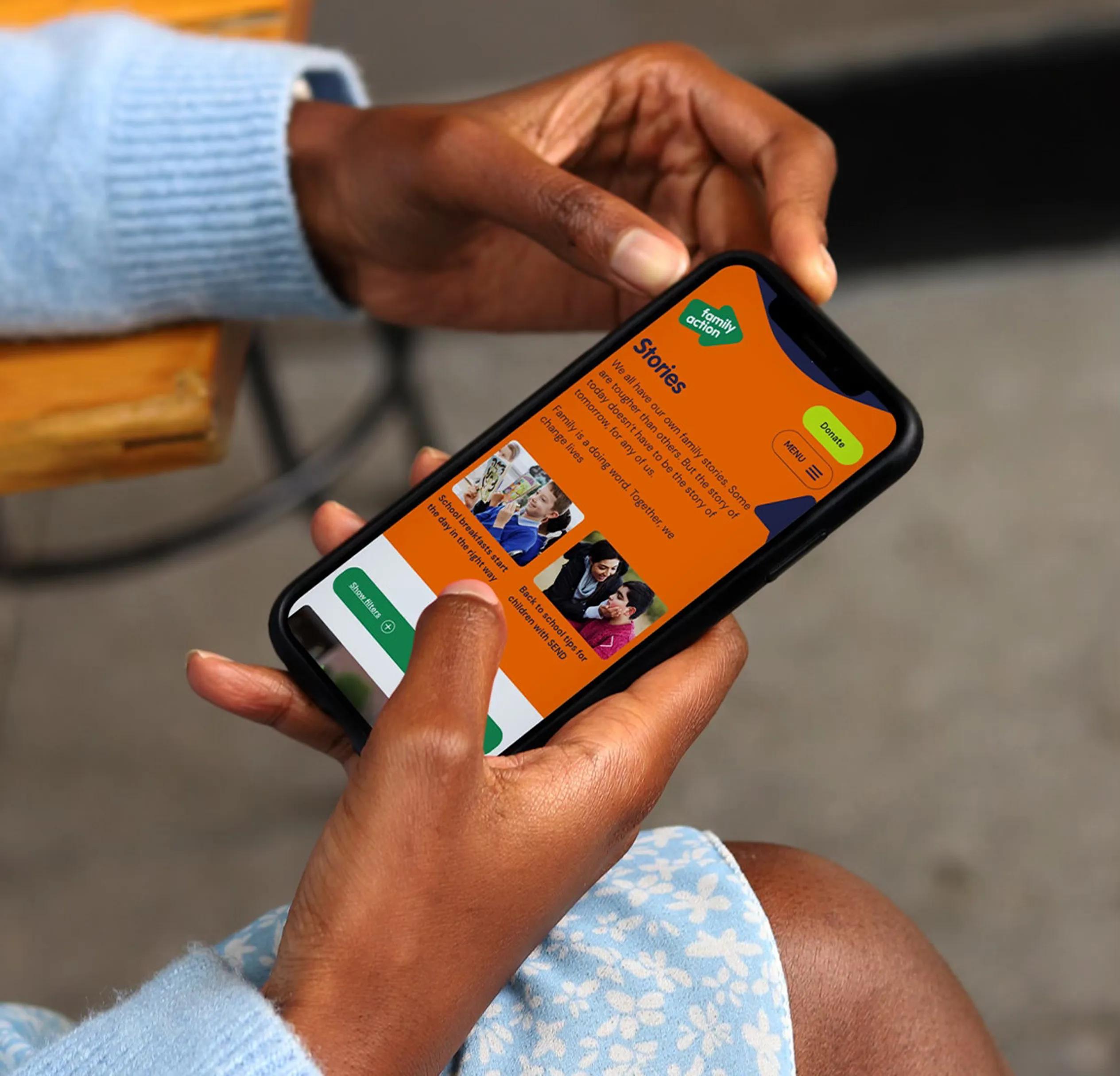 Person holding phone with family action website on it