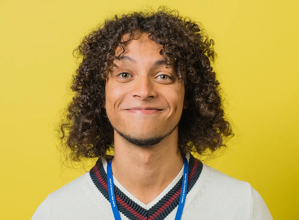 Male student smiling at the camera with a yellow background